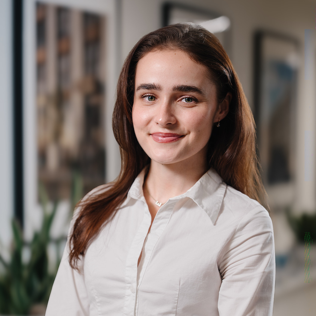 Portrait of a smiling dark haired woman in a white shirt in an office
