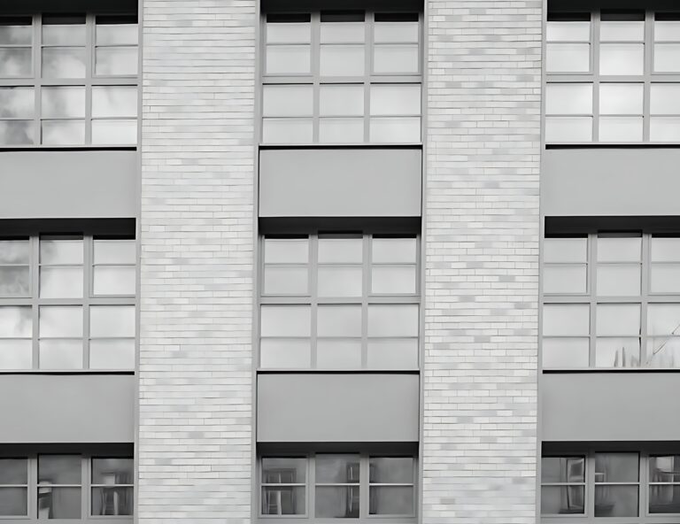 Černobílý detail fasády s bílými cihlovými pilíři a velkými okny