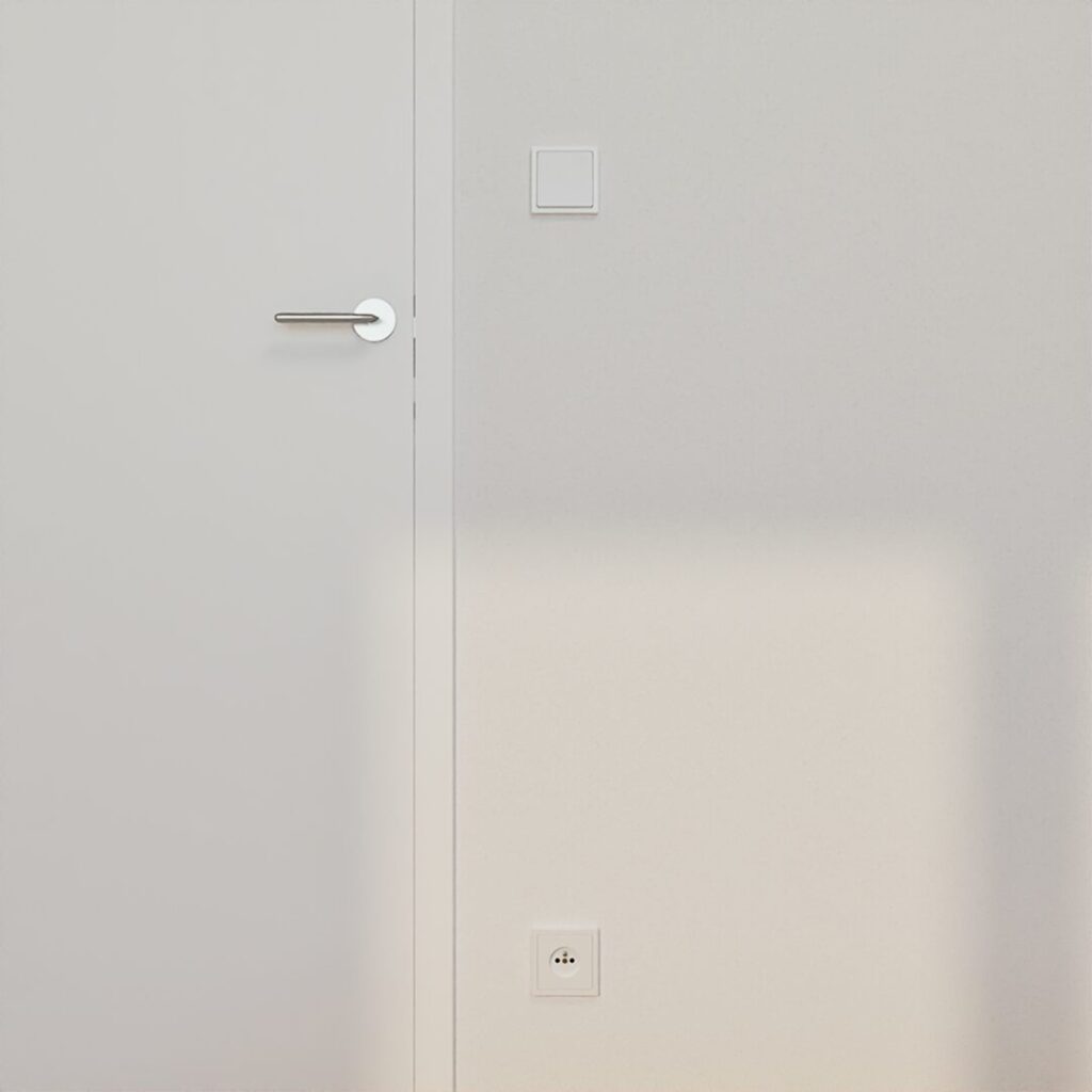 Close-up of a white interior door with a stainless steel handle, a light switch and a power outlet