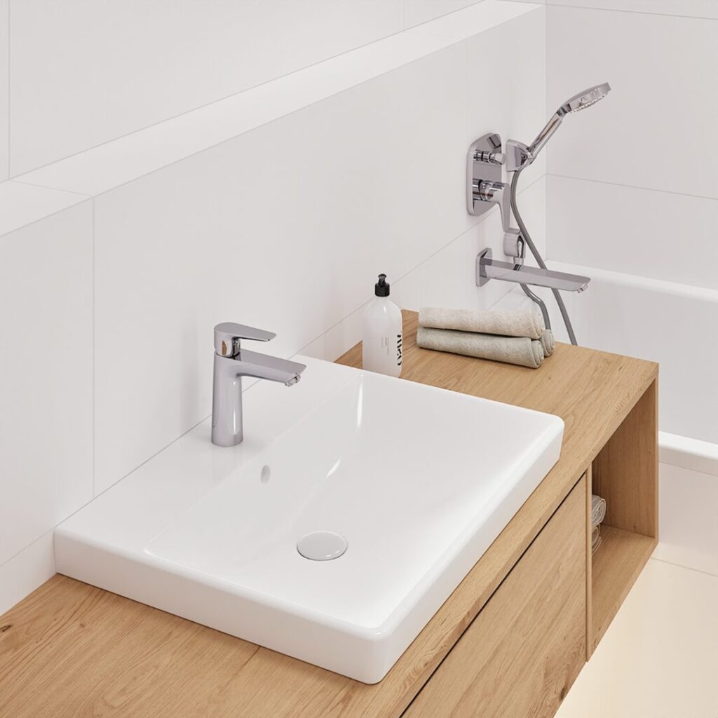 Close-up of a white sink on a wooden countertop with a chrome faucet and a bathtub